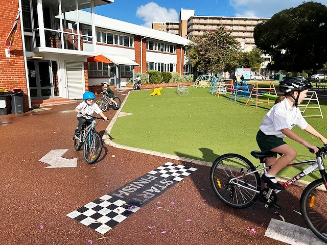 Three students riding bicycles on school driveway