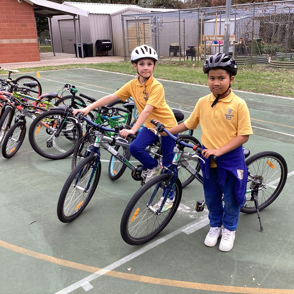 Two primary school students with bikes on a school basketball court